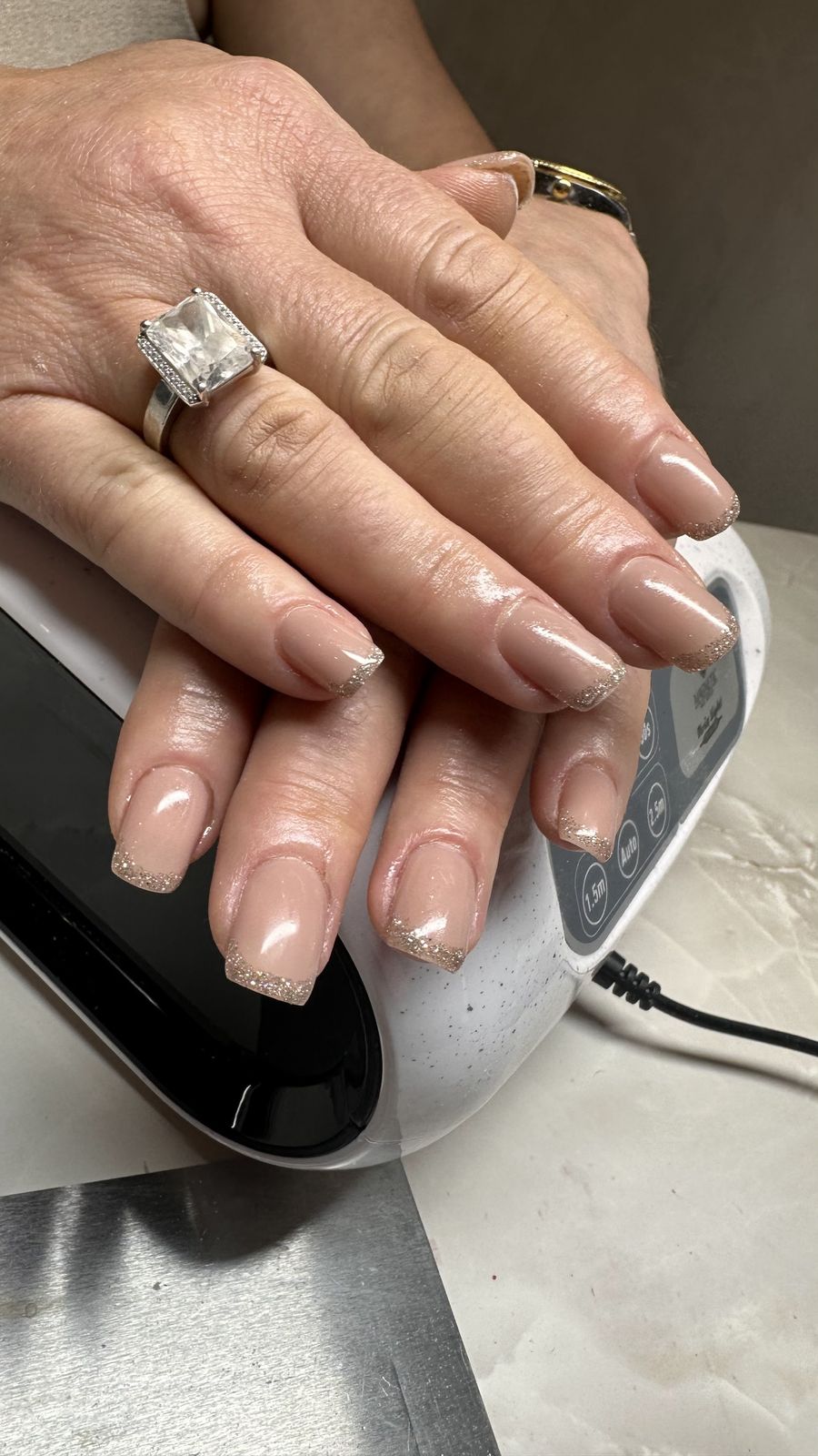 Nude amandelnagels, handen rustend op een nagellamp